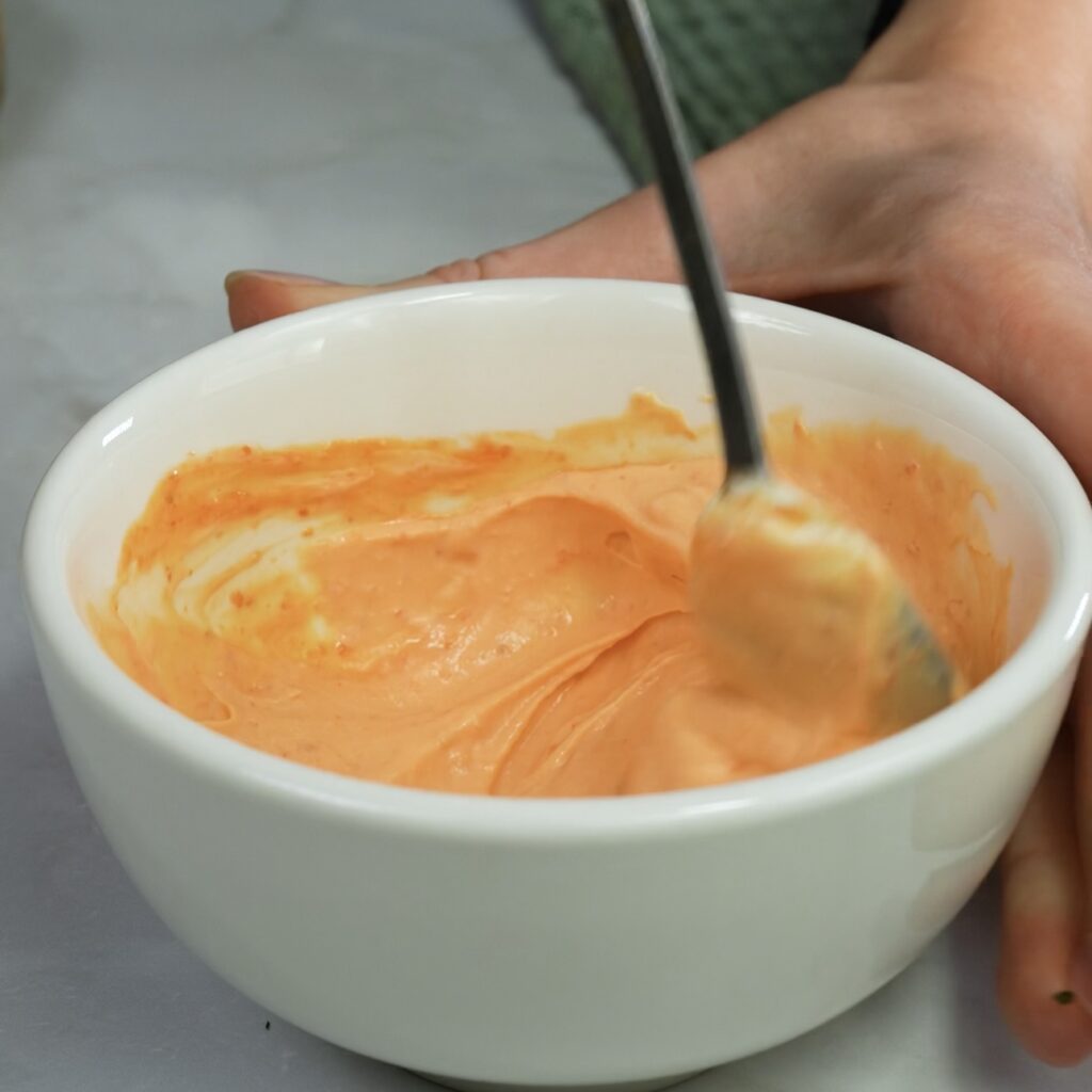 Mixing cream cheese, yogurt, and sriracha for the spicy topping.