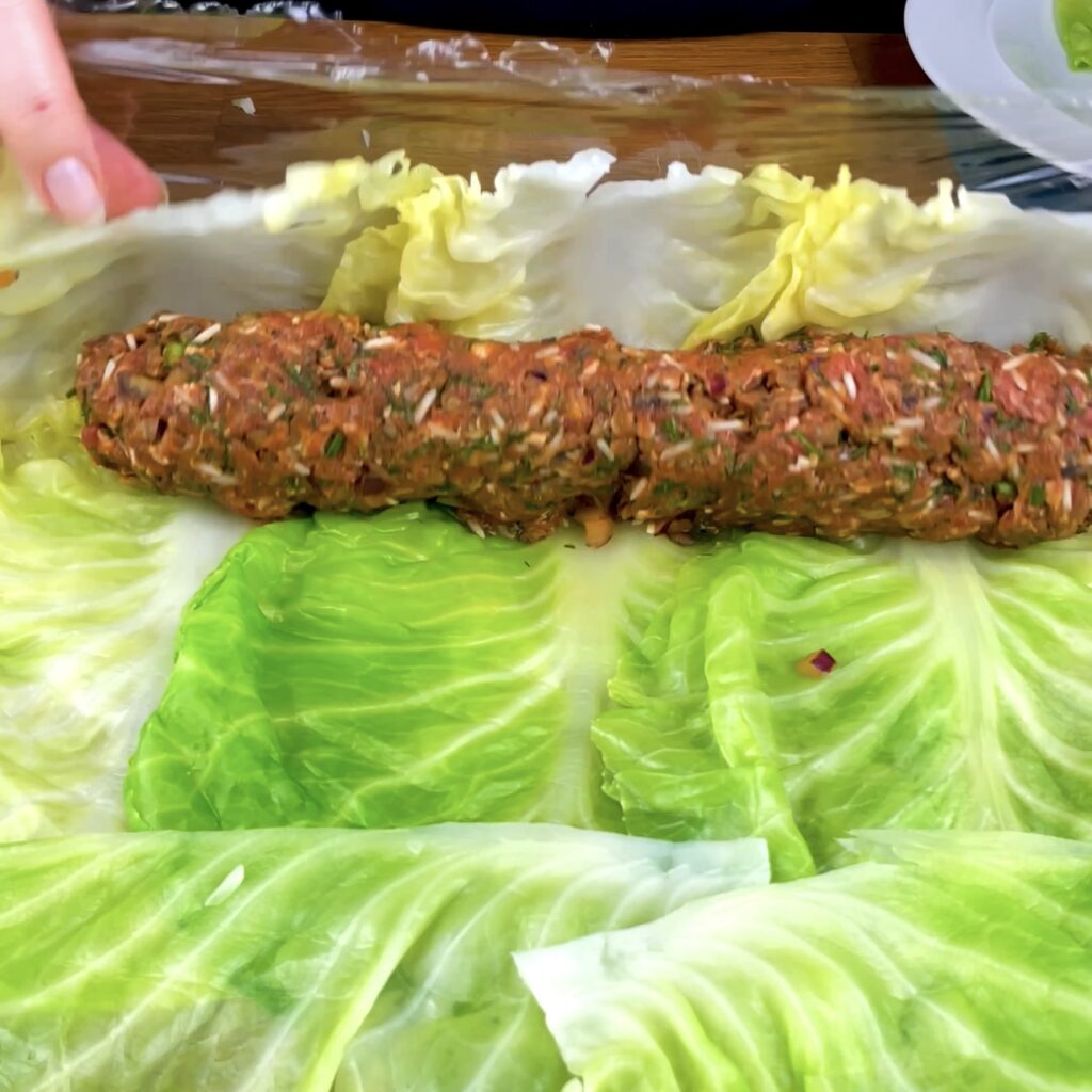 Rolling cabbage leaves around the filling to create giant cabbage rolls.