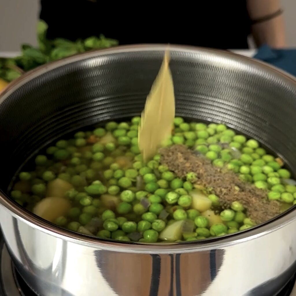 Frozen peas, stock, and seasonings in a pot.