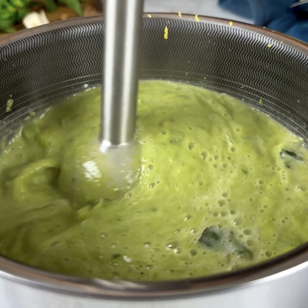 Blending the soup with an immersion blender.