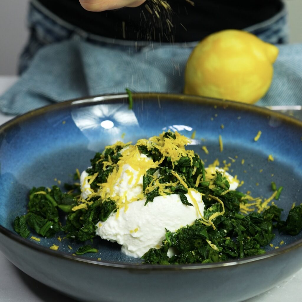 Mixing spinach, ricotta, lemon zest, salt, and pepper in a bowl.