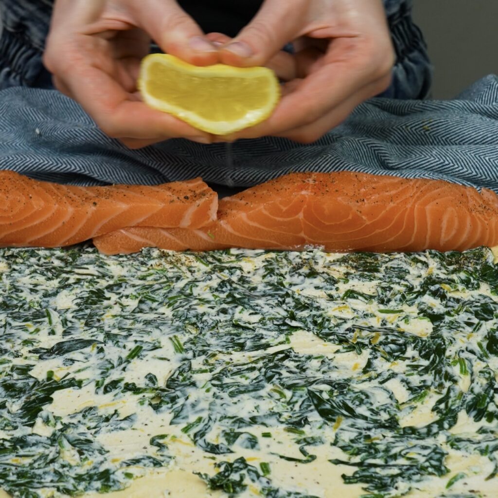 Seasoned salmon fillets placed on top of the spinach filling.