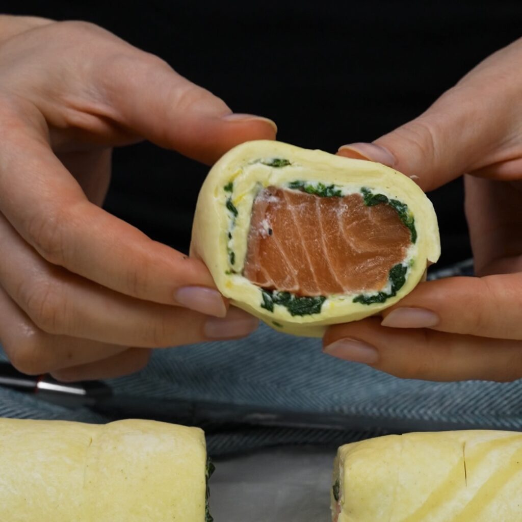 Slicing the filled puff pastry roll into smaller pieces.