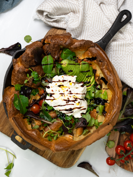 Salmon Dutch Baby with fresh salad, avocado, burrata, and cherry tomatoes.