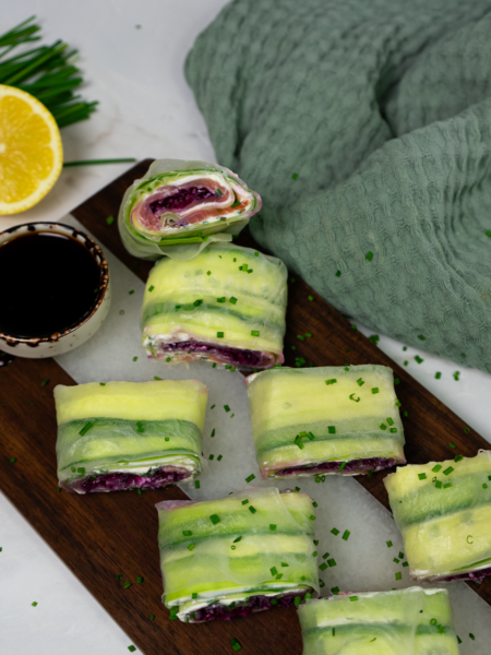 A finished rice paper cucumber roll filled with smoked salmon, cucumber, cream cheese, and red cabbage.