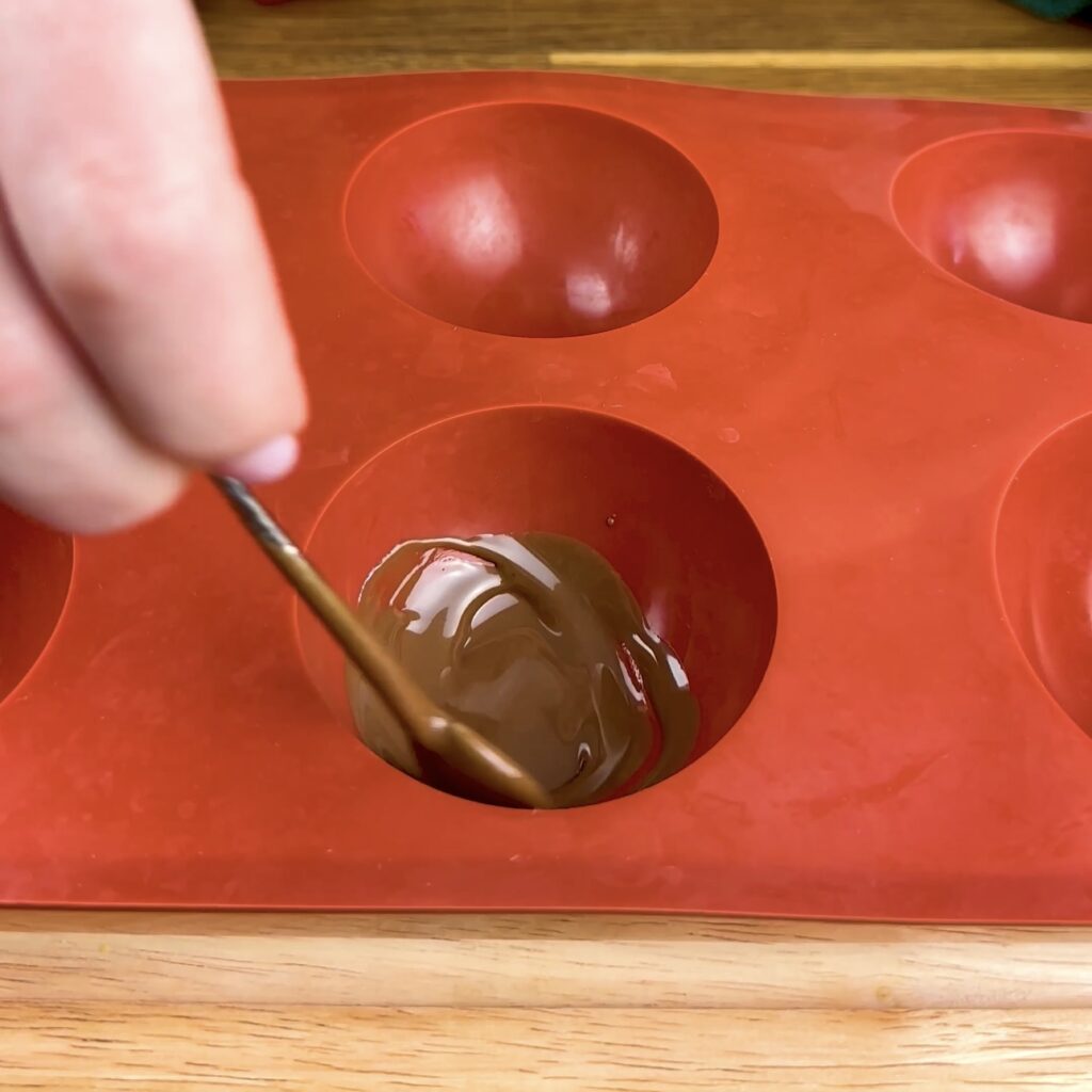 Filling the silicone mould cavities with melted chocolate.