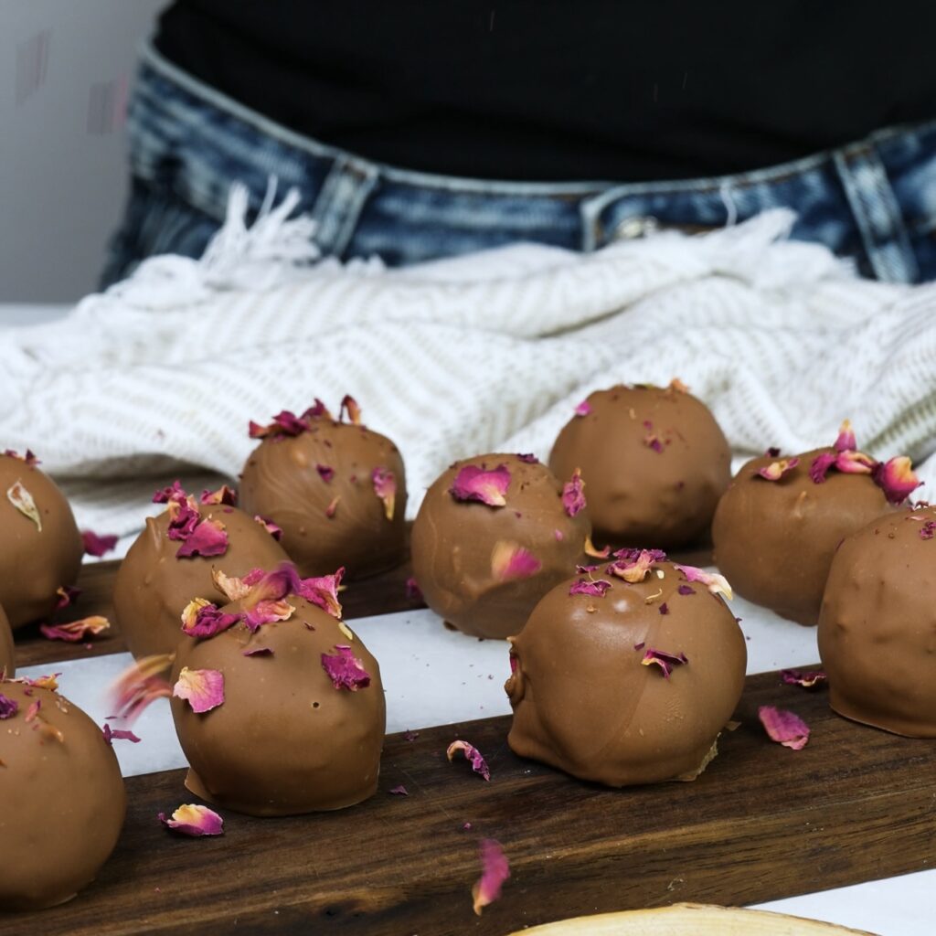 Sprinkling rose petals on chocolate-coated treats.