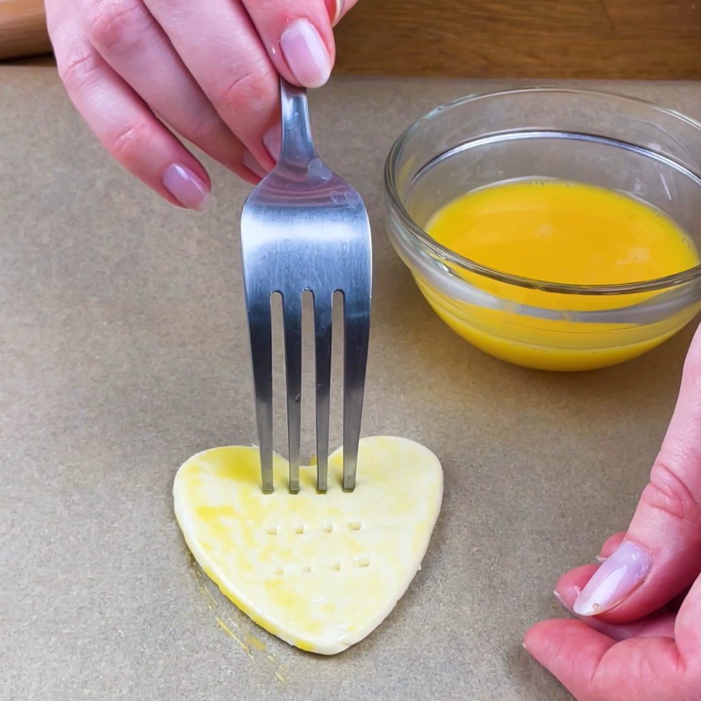 Pricking puff pastry hearts with a fork before baking.