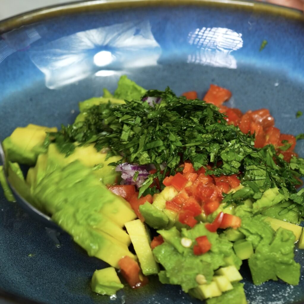 Mixing avocado, red onion, cherry tomatoes, lime juice, and jalapeño for a fresh salsa.