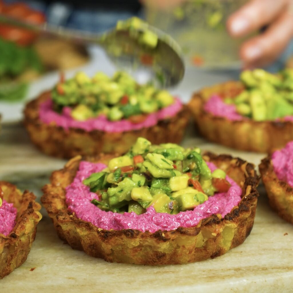 Filling crispy potato tart shells with beetroot feta mixture and topping with avocado salsa.