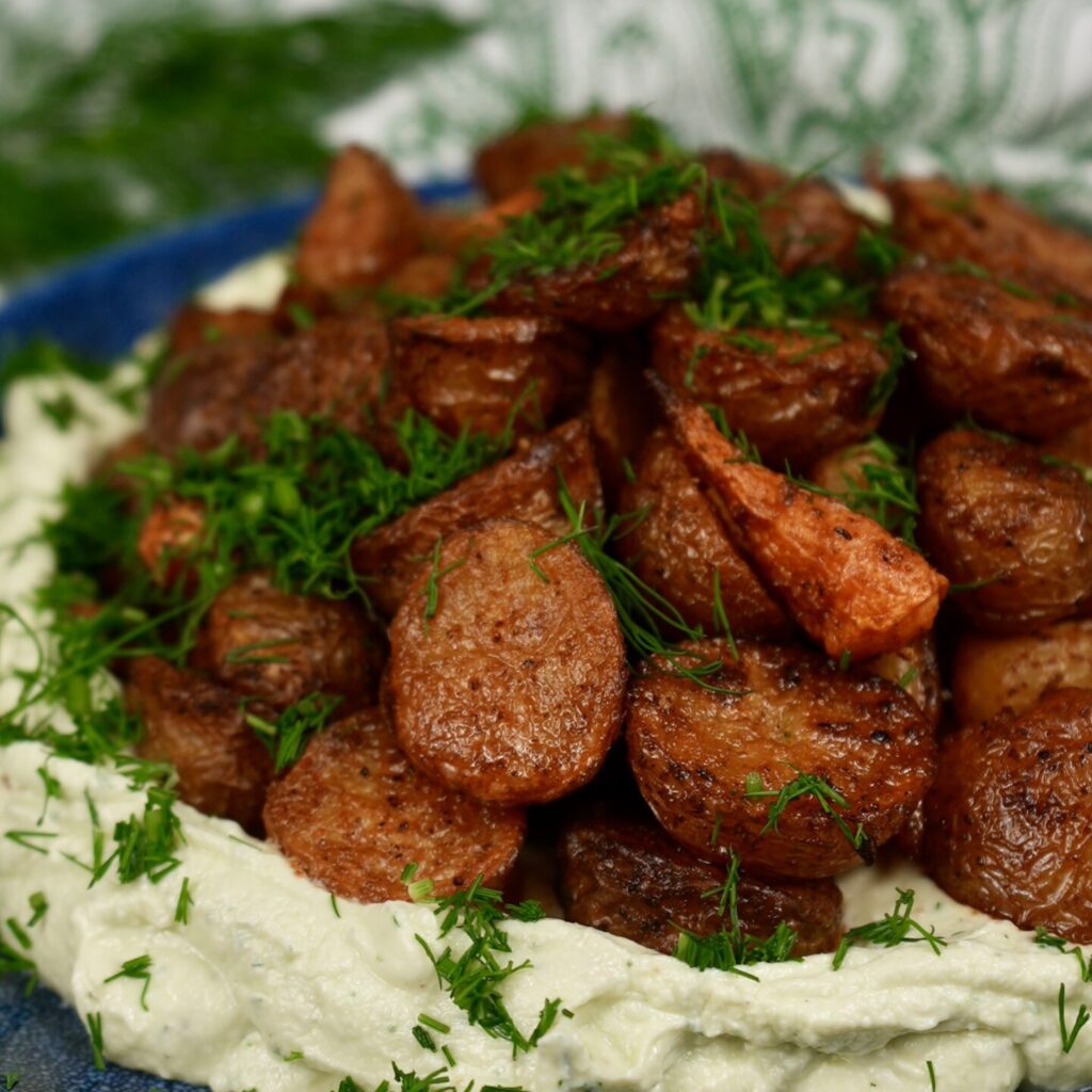 Roasted baby potatoes and carrots on whipped feta, garnished with dill