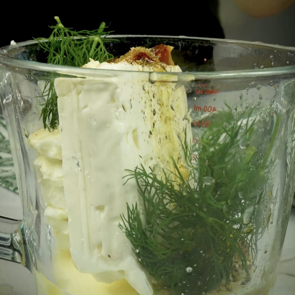 Blending feta with cream, garlic, lemon juice, and dill in a food processor
