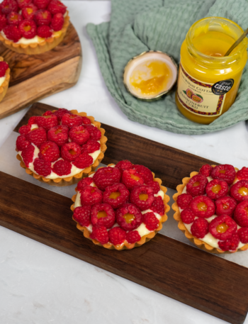 Passion Fruit Curd and Raspberry Tarts topped with fresh raspberries and curd.