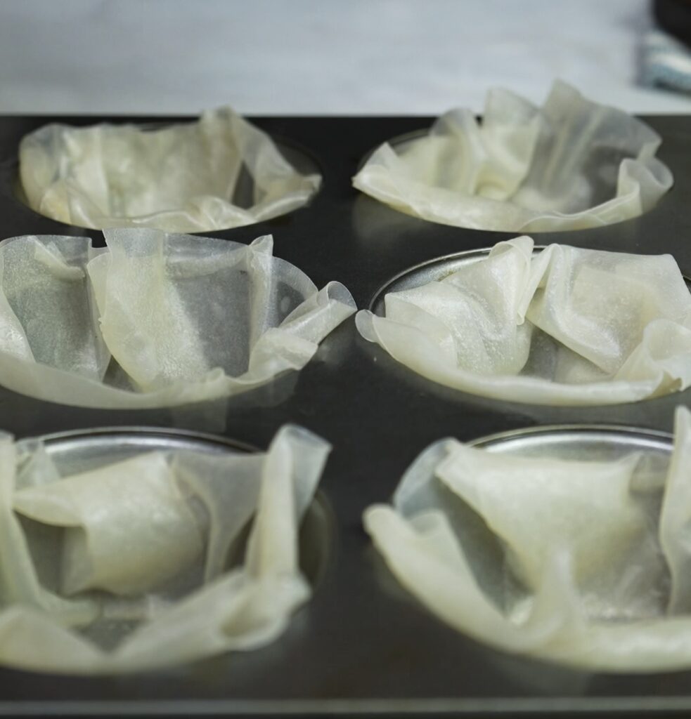 Pressing rice paper into a muffin tin