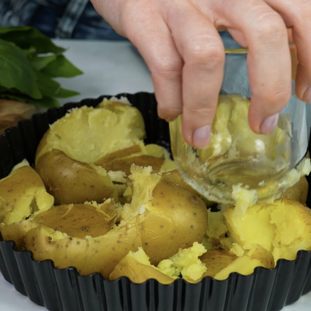 Crushing boiled potatoes into a quiche tin