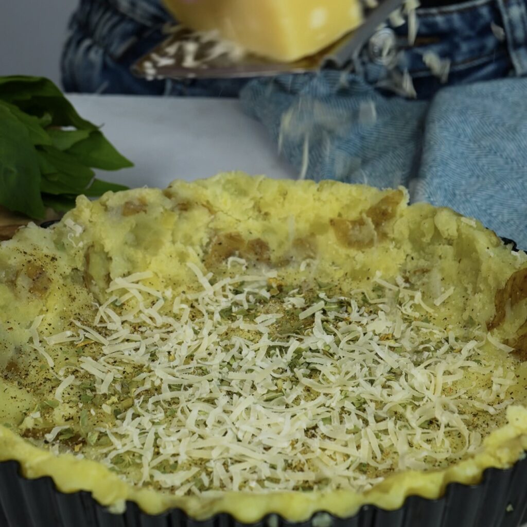 Grating Parmesan cheese over potato crust