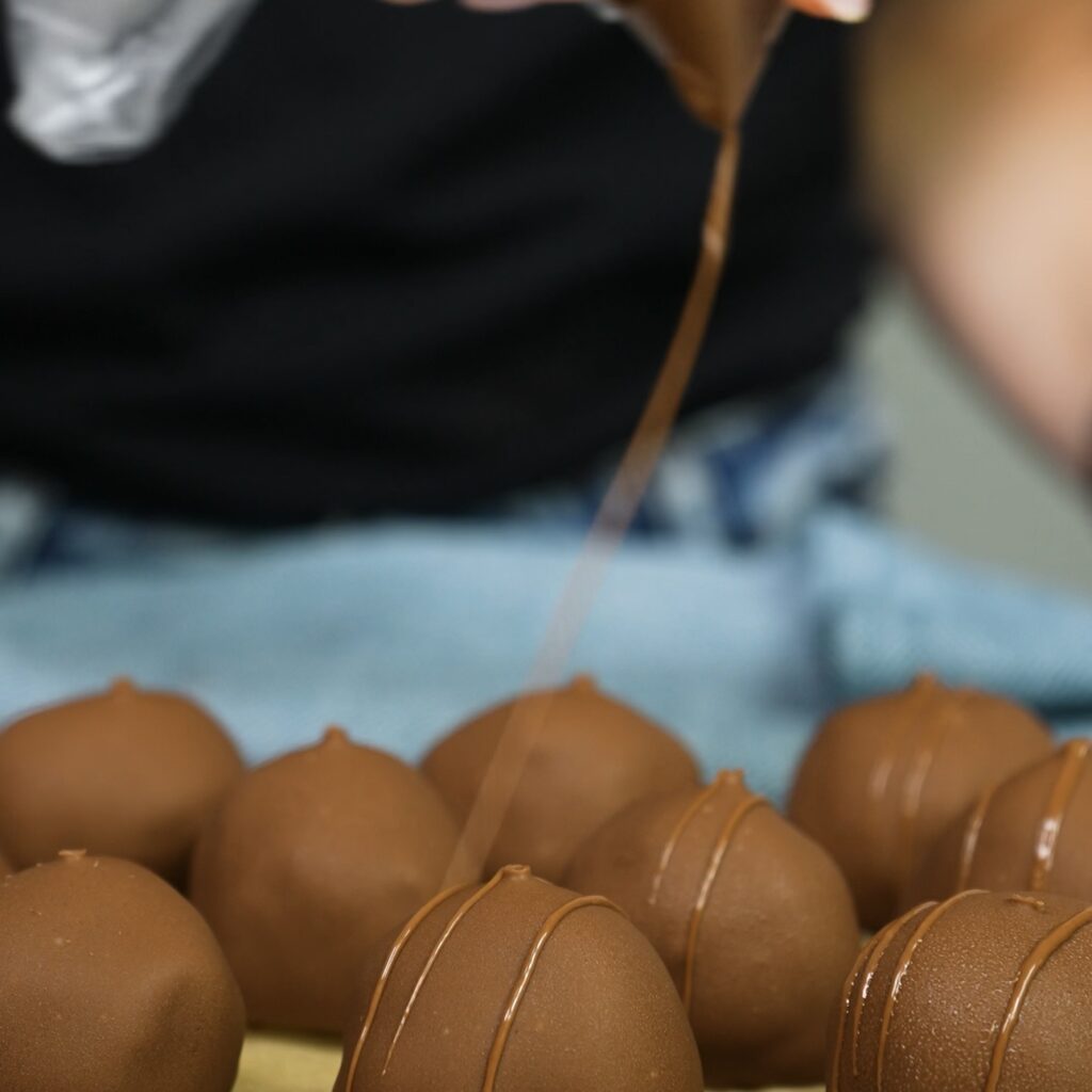 Drizzling remaining chocolate over coated cottage cheese date bites