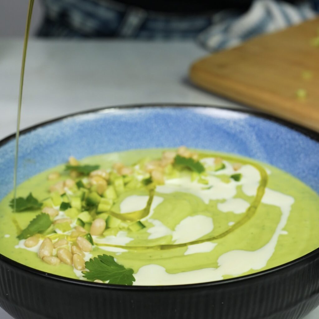 Topping chilled avocado soup with cucumber, pine nuts, and chilli flakes