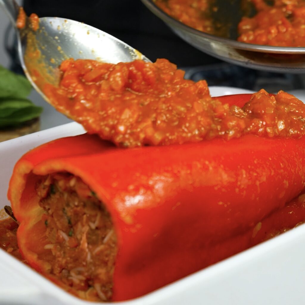 Stuffed pepper in baking dish with sauce
