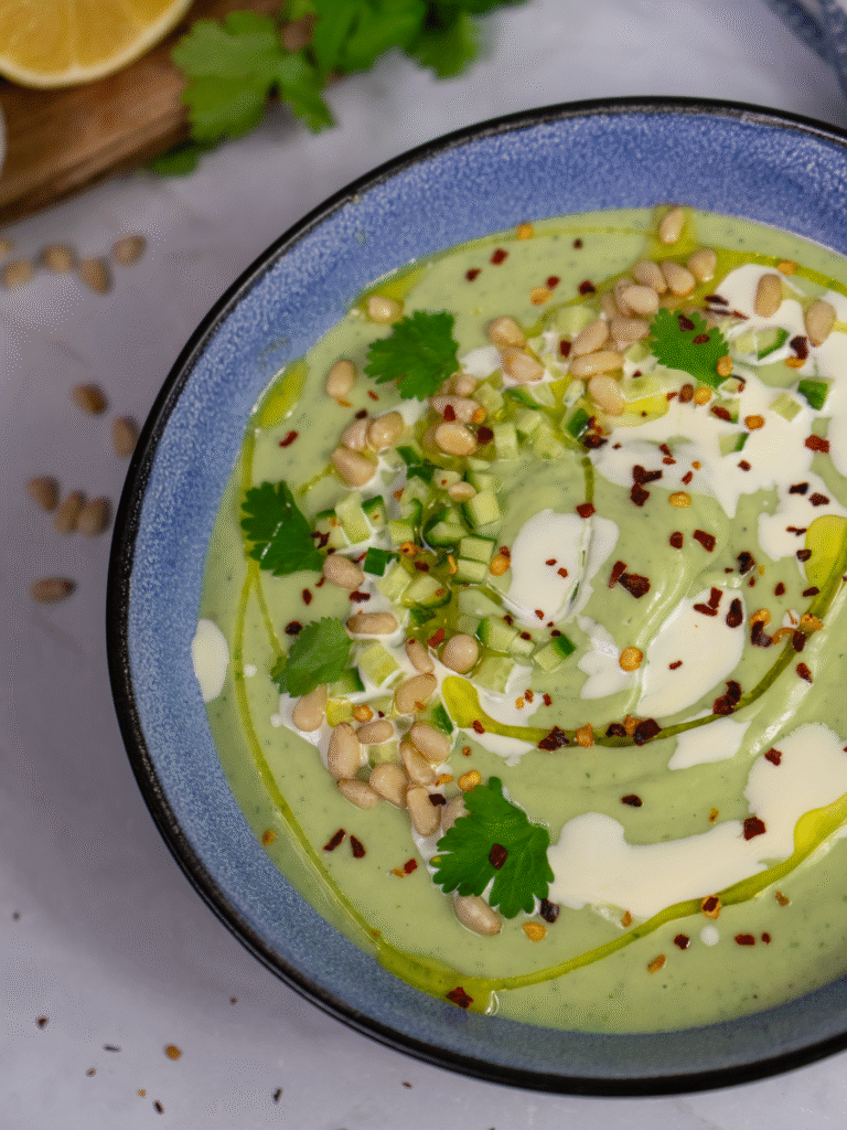 Chilled avocado soup topped with cucumber, pine nuts, chilli flakes, and coriander