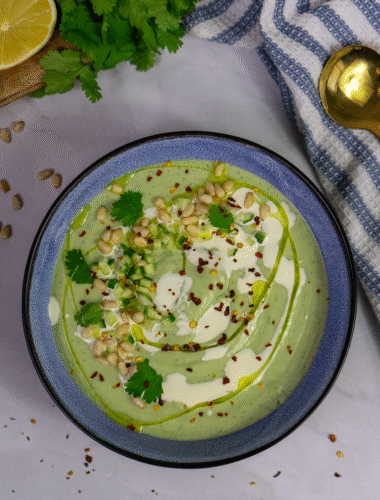 Chilled avocado soup topped with cucumber, pine nuts, chilli flakes, and coriander
