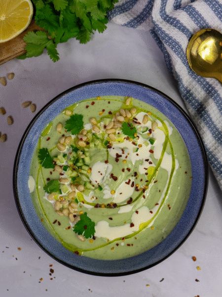 Chilled avocado soup topped with cucumber, pine nuts, chilli flakes, and coriander