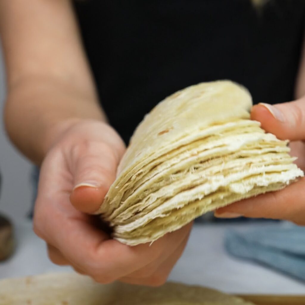 Twelve round tortilla circles cut from large flour tortillas, ready for baking.