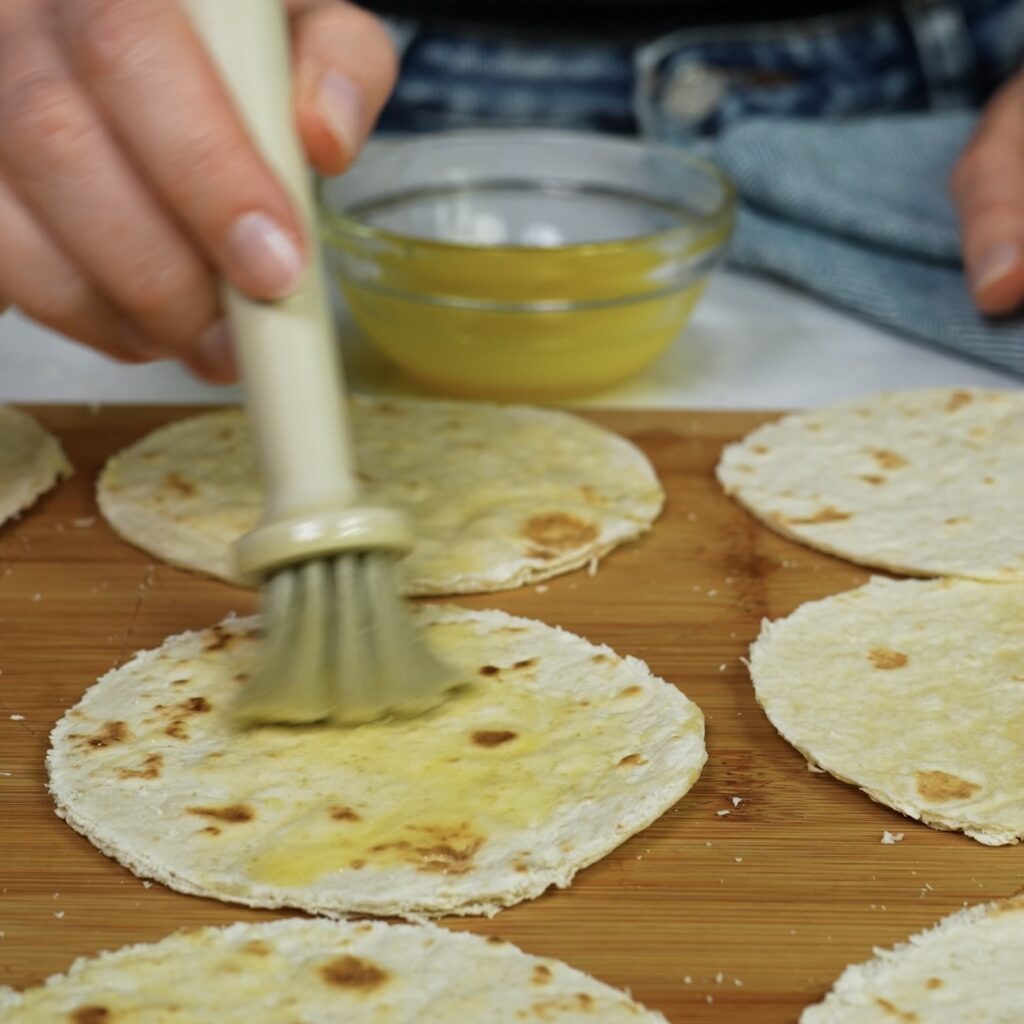 Tortilla circles being brushed with butter and honey glaze.