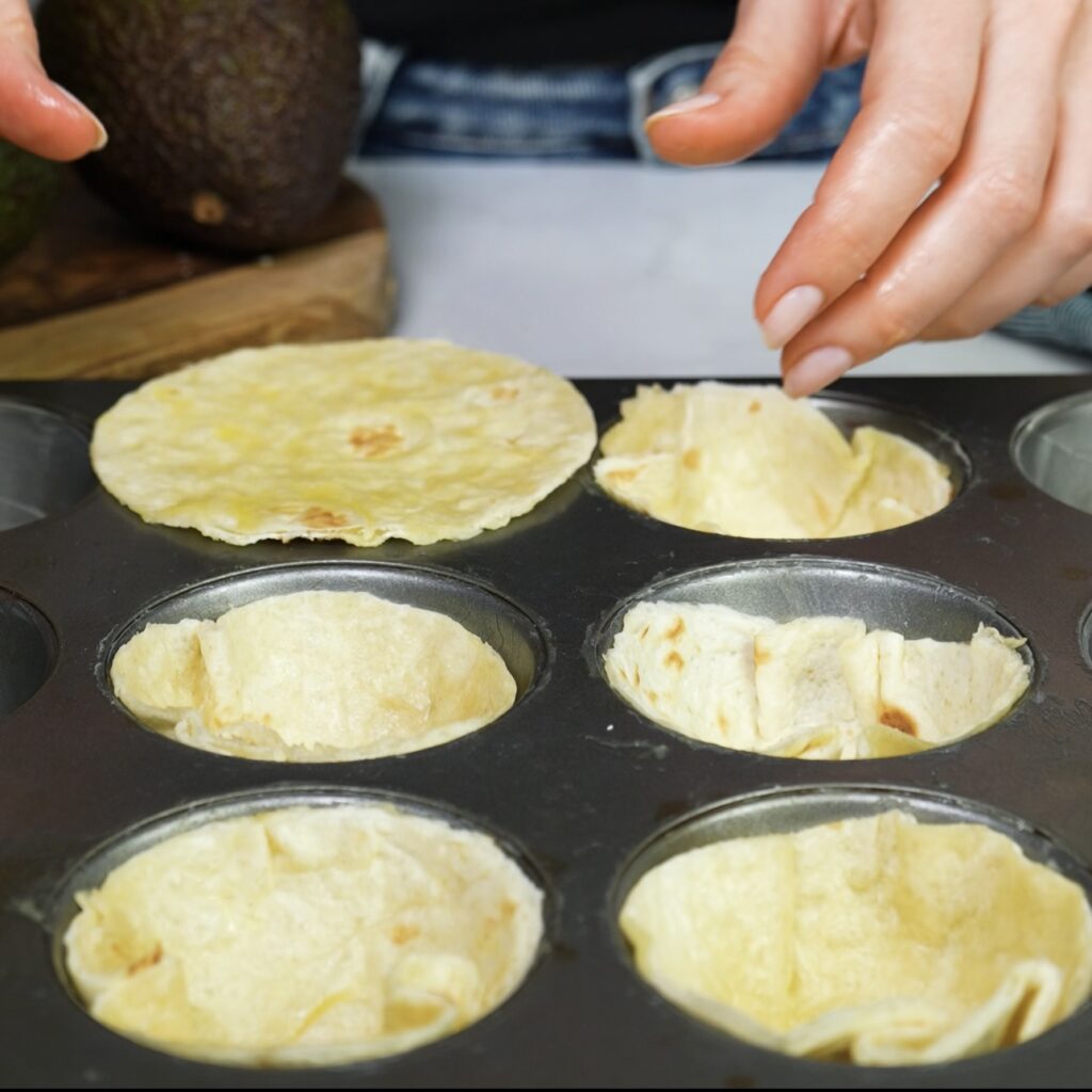 Tortilla circles pressed into a muffin tin to form cups.