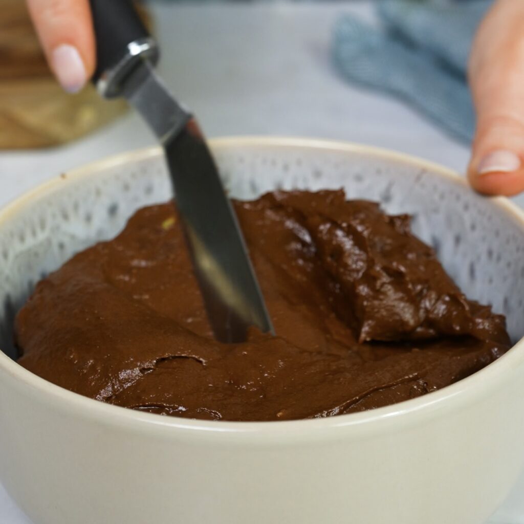 Chocolate avocado mousse blended smooth in a mixing bowl.