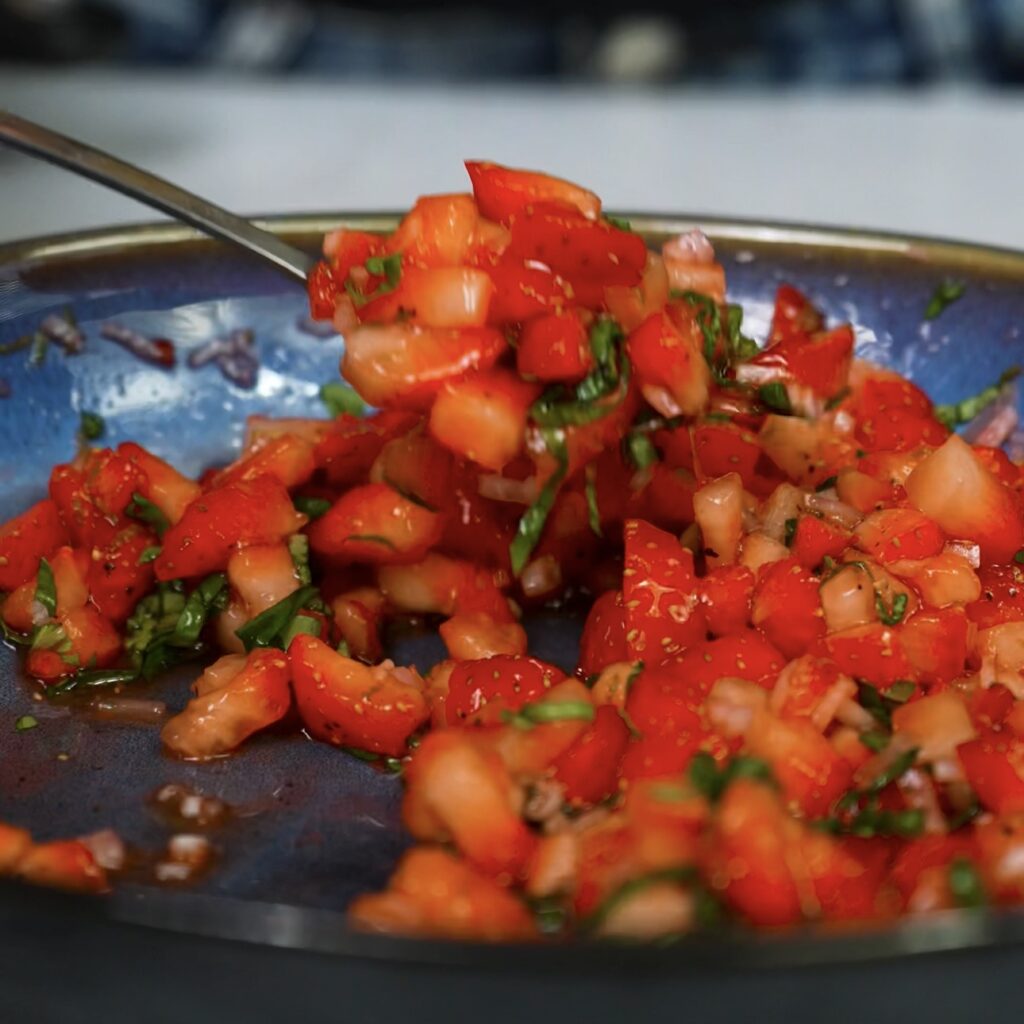 Fresh strawberry salsa in a bowl with herbs