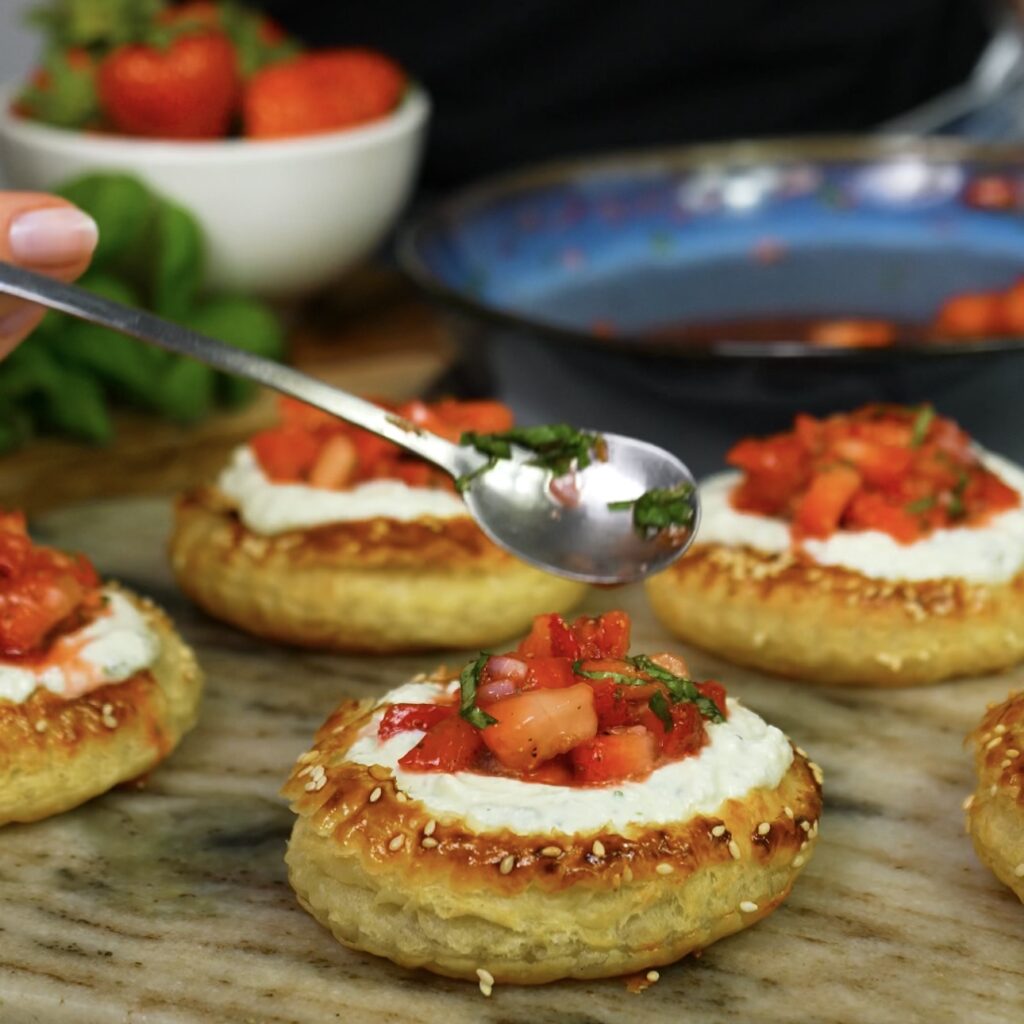 Spoon adding whipped cottage cheese and strawberry salsa to puff pastry tart