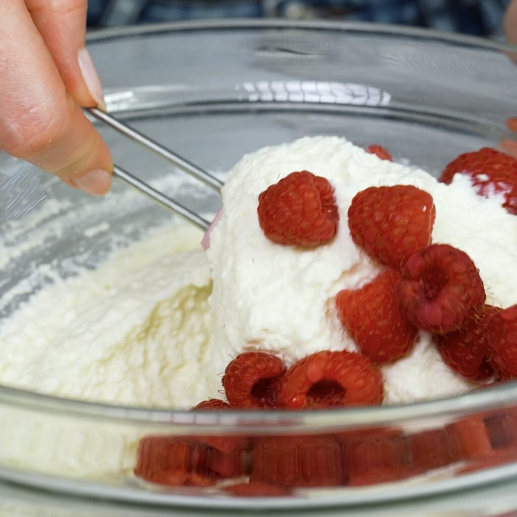 Gently folding fresh raspberries into sweetened cottage cheese mixture