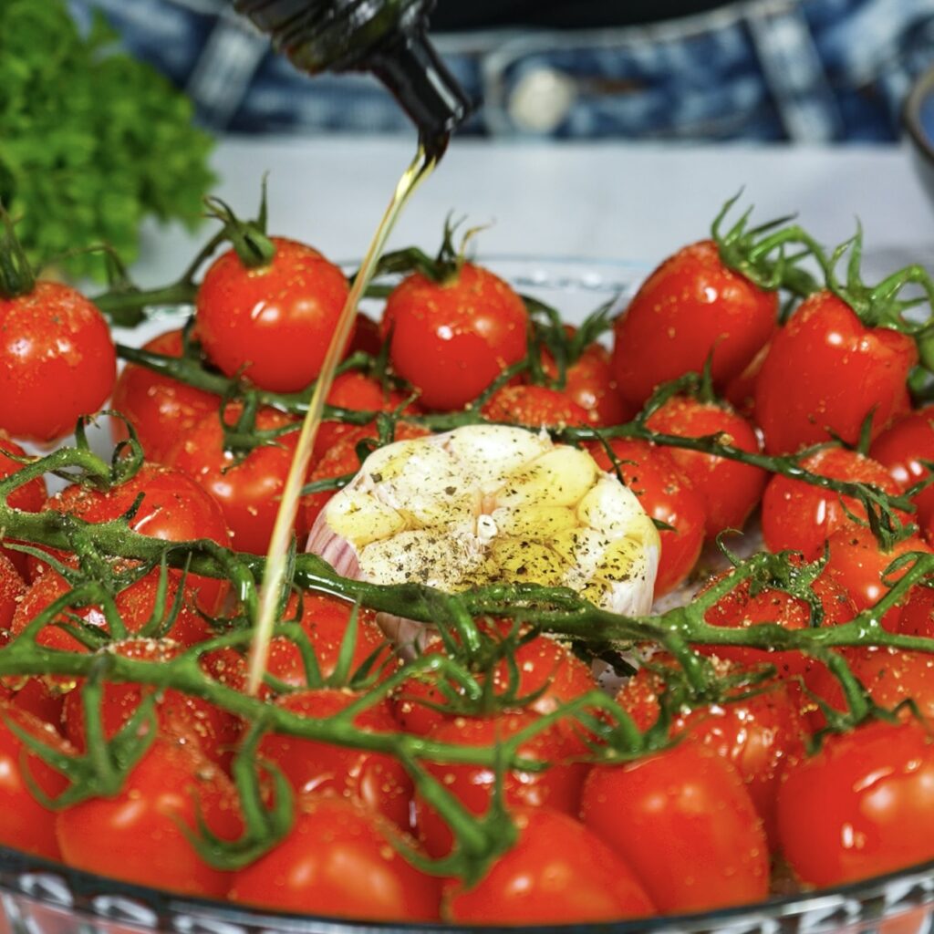 Drizzling olive oil over cherry tomatoes and garlic before roasting
