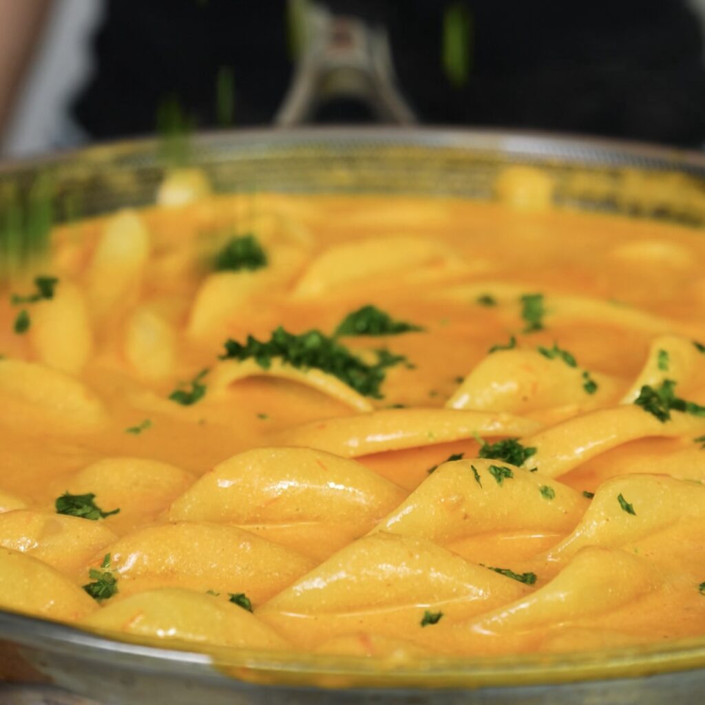 Cooked fusilli pasta tossed in a pan with creamy tomato sauce