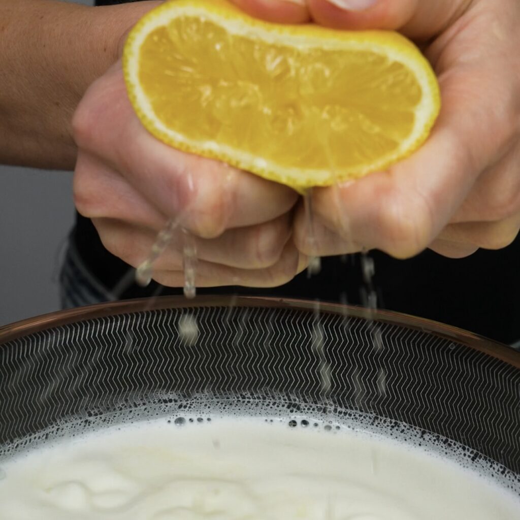 Squeezing lemon juice into warm milk to make cottage cheese