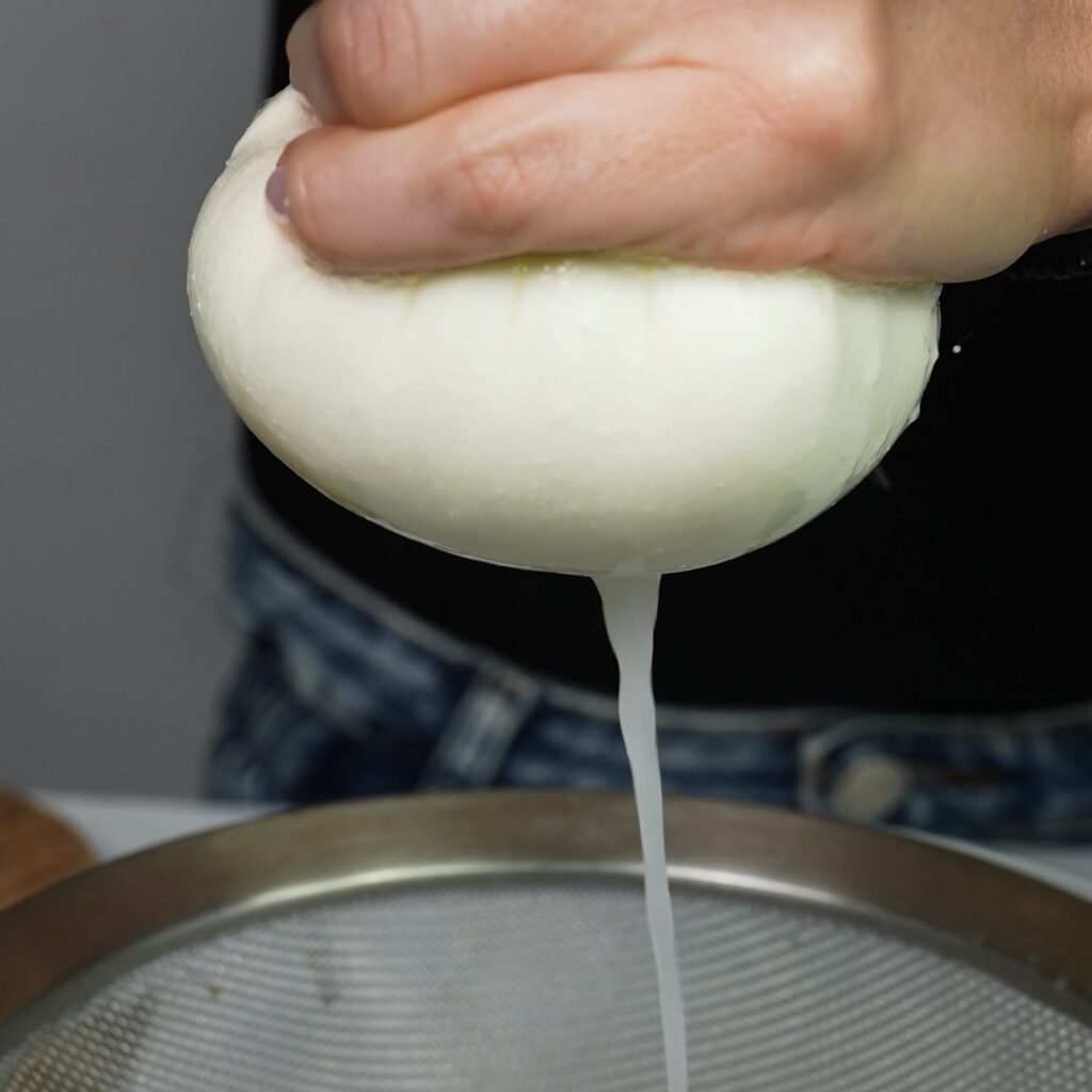 Squeezing cottage cheese bundle before draining
