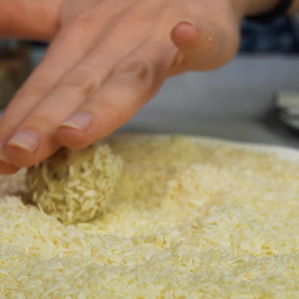 Rolling cottage cheese bites in desiccated coconut flakes