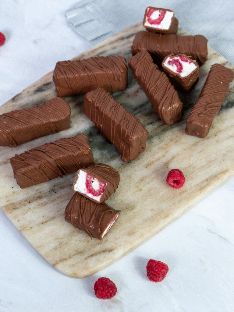 Raspberry cottage cheese bars arranged on a marble board with a few bars cut and separated