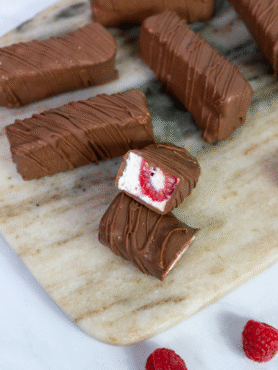 Raspberry cottage cheese bars arranged on a marble board with a few bars cut and separated