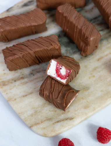 Raspberry cottage cheese bars arranged on a marble board with a few bars cut and separated