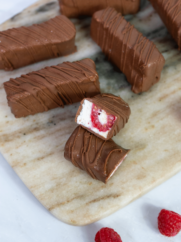 Raspberry cottage cheese bars arranged on a marble board with a few bars cut and separated