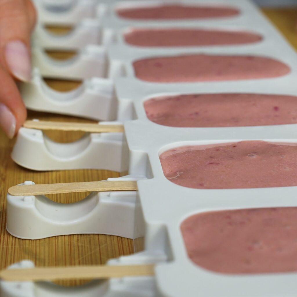 Inserting wooden sticks into cherry ice cream moulds