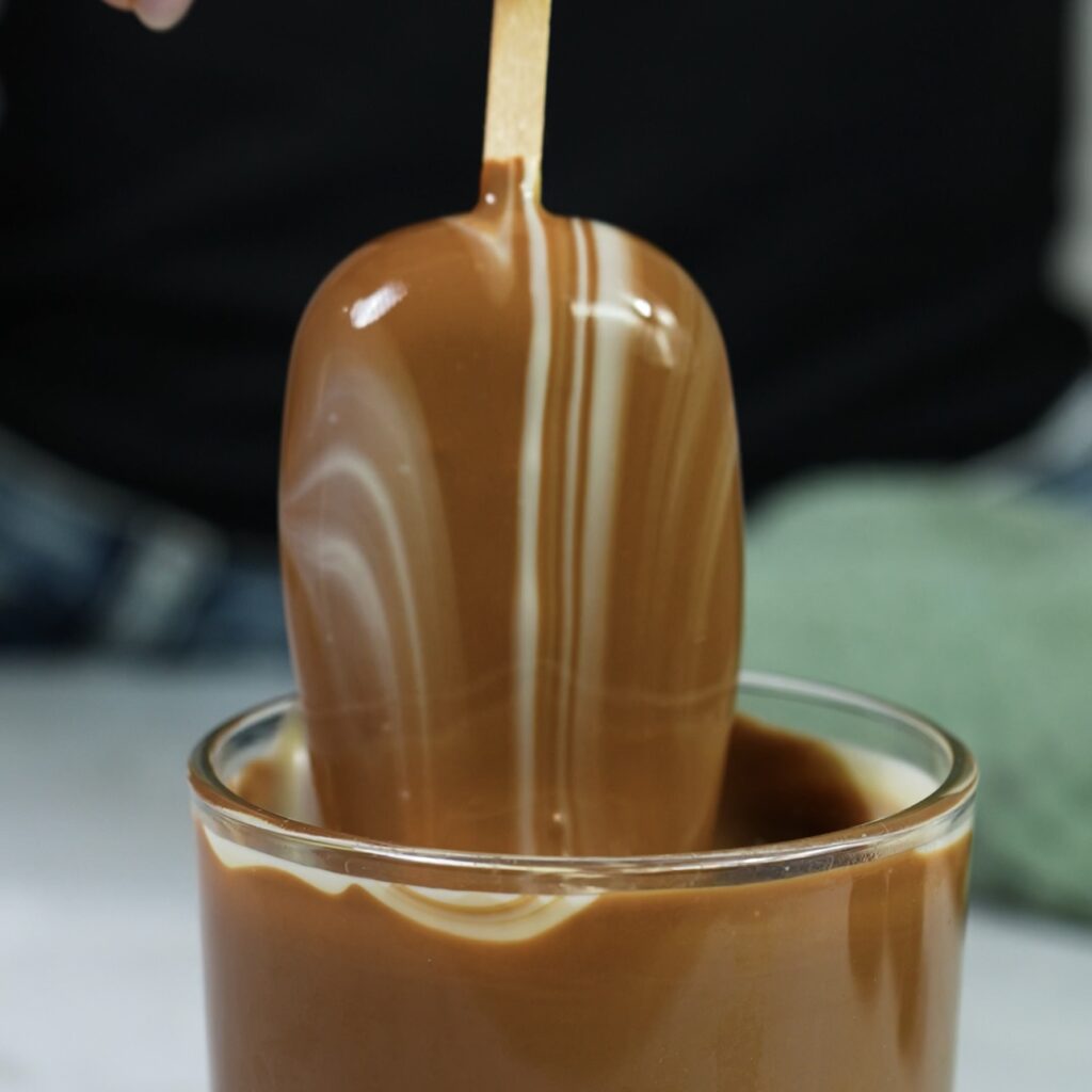 Dipping cherry cottage cheese ice cream into chocolate