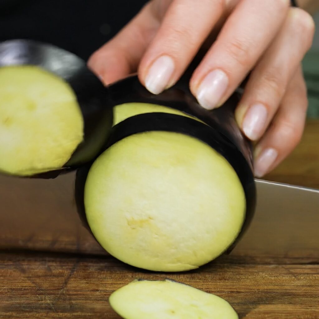 Slicing fresh aubergine into thin rounds for tacos