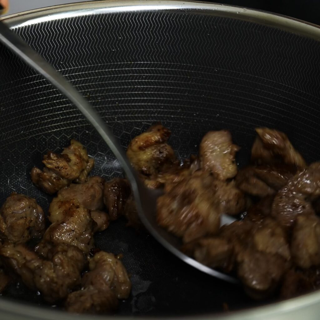 Lamb pieces browning in a Dutch oven with olive oil and butter.