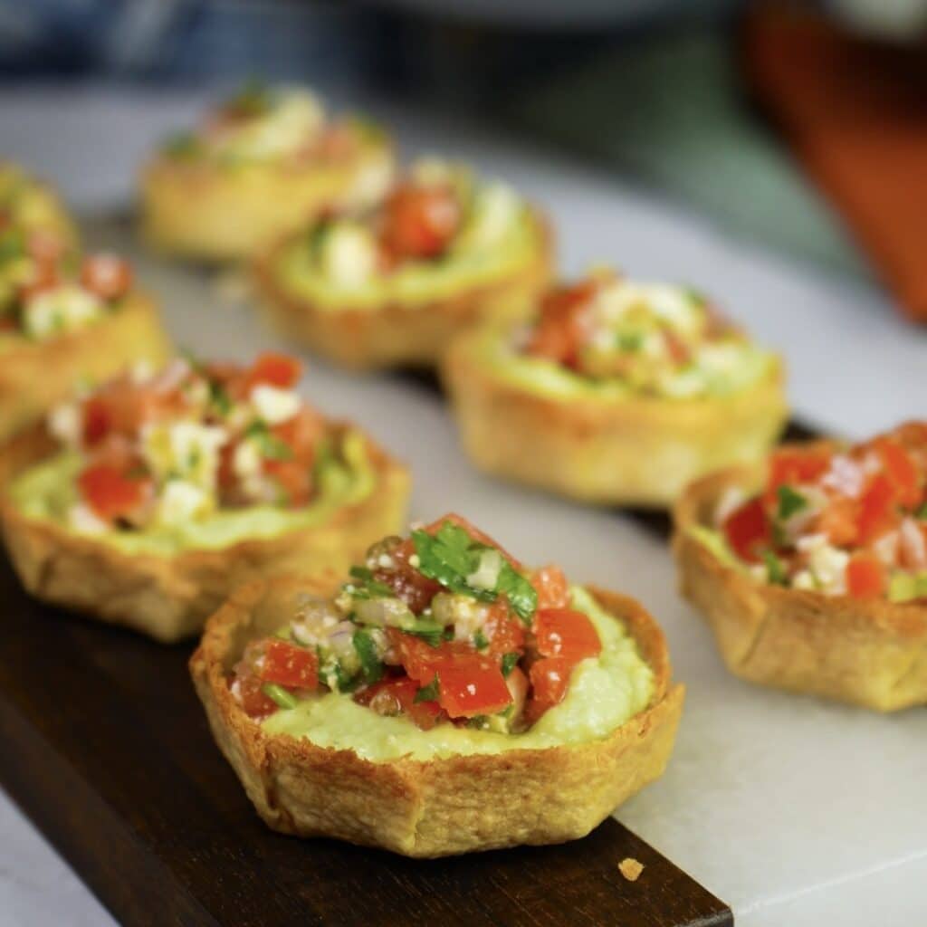 Tortilla cups filled with avocado mousse and topped with tomato and feta mixture