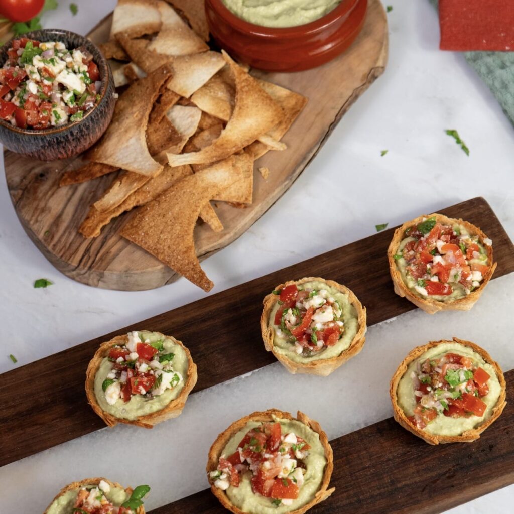 Tortilla cups filled with avocado mousse and tomato feta topping served with crispy tortilla chips