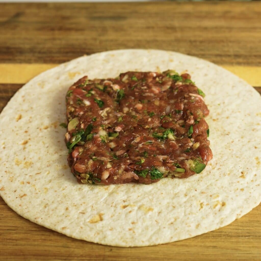 Spiced minced beef filling shaped into a neat square on a tortilla.