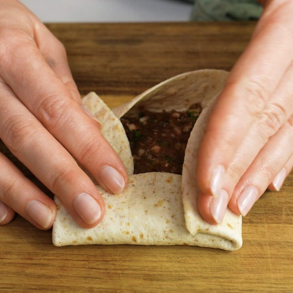 Making the final fold to secure the tortilla parcel.